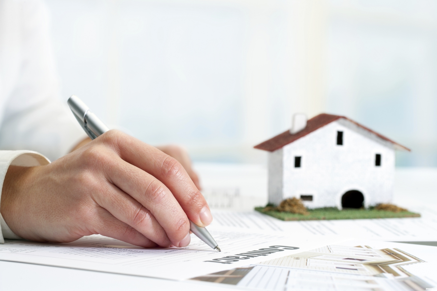 một người cầm bút ký vào giấy tờ mua bán nhà đất